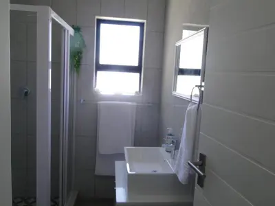 a white bathroom with a sink and a window at Fresh Air in Cape Town