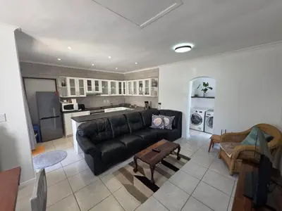 a living room with a black couch and a kitchen at Alvera in Strand