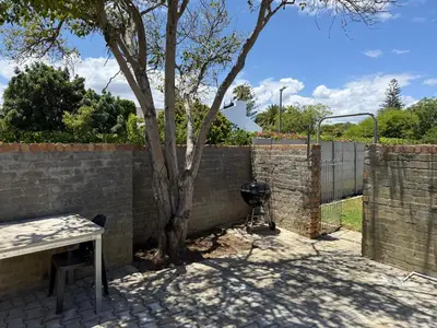 a barbecue grill next to a brick fence with a tree at Welcome Home in Somerset West