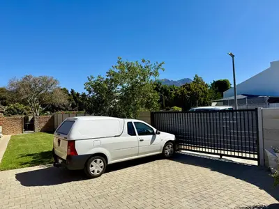 a white car parked next to a fence at Welcome Home in Somerset West