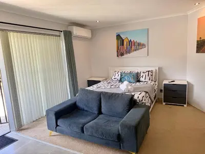 a bedroom with a bed and a blue couch at Welcome Home in Somerset West