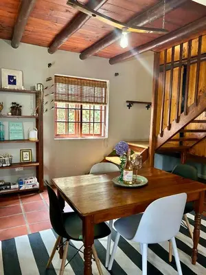 a dining room with a wooden table and chairs at The Little Thatch Cottage in Greyton