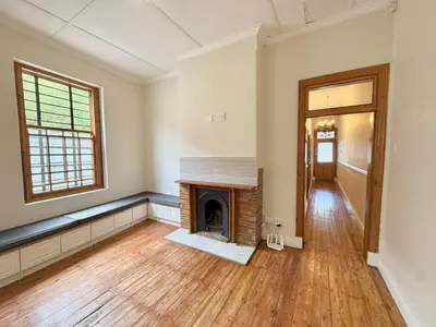 an empty living room with a fireplace and wooden floors at 3 Bedroom Vintage Home in Cape Town
