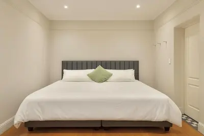 a large white bed with a green pillow on it at 3 Bedroom Vintage Home in Cape Town