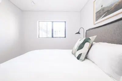 a white bedroom with a bed and a window at 116 Paarl - Lux 1 Bedroom Apt with AC and Parking in Paarl
