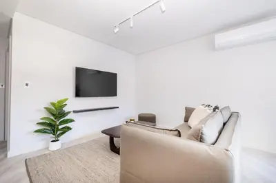 a living room with a couch and a tv on a wall at 116 Paarl - Lux 1 Bedroom Apt with AC and Parking in Paarl