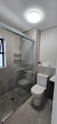 a bathroom with a toilet and a glass shower at Ebbies place in Cape Town