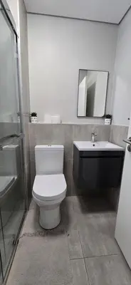 a bathroom with a toilet and a sink and a mirror at Ebbies place in Cape Town