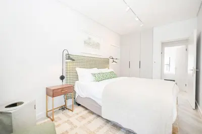 a white bedroom with a white bed and a table at 213 Paarl 2 Bedroom Lux Aprt With Parking & Aircon in Paarl