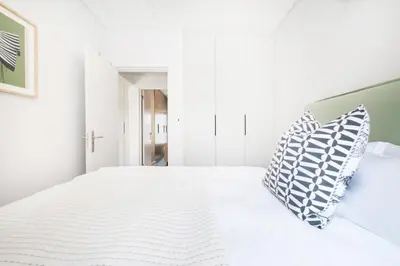 a white bedroom with a bed with two pillows at 213 Paarl 2 Bedroom Lux Aprt With Parking & Aircon in Paarl