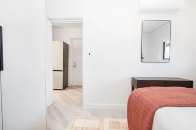 a white bedroom with a bed and a mirror at 216 Paarl Lux 1 Bdrm Apt with Parking and AC in Paarl