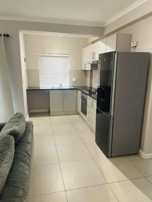 a kitchen with a stainless steel refrigerator and a couch at Cape Coral in Cape Town