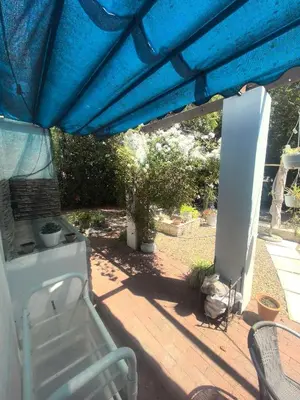 a patio with a blue umbrella and a bench under it at 22 on BREEZAND in Cape Town