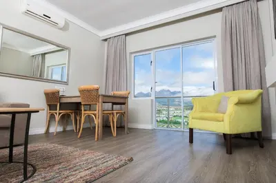 a living room with a table and chairs and a large window at Protea Hotel by Marriott Stellenbosch & Conference Centre in Stellenbosch