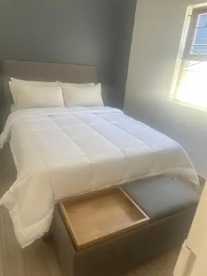 a large white bed with a wooden tray on it at Milino Guest House in Cape Town