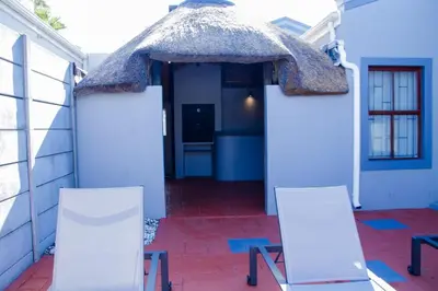 a house with two chairs and a thatch roof at Milino Guest House in Cape Town