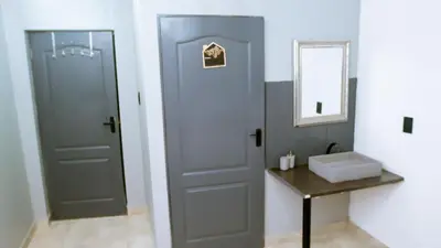 a bathroom with a door and a sink and a mirror at DC Guest House in Avondale