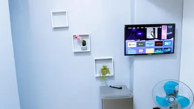 a room with a fan and a tv on a wall at DC Guest House in Avondale