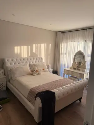 a bedroom with a large white bed with a teddy bear on it at Durbanville apartment in Durbanville