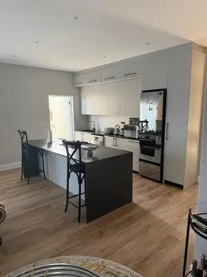 a kitchen with white cabinets and a table and chairs at Durbanville apartment in Durbanville