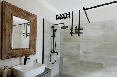 a bathroom with a shower and a sink and a mirror at Coats Haven in Hermanus