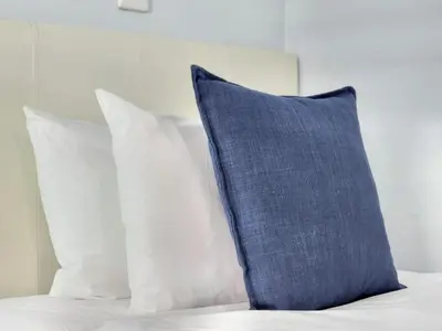 a blue pillow sitting on a bed with white pillows at Seaside Serenity with Ocean View in Cape Town