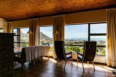 a dining room with a table and chairs and windows at Hillside View in Pringle Bay