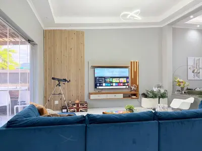 a living room with a blue couch and a tv at Centrally located 11 sleeper house near Canal Walk in Cape Town