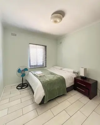 a bedroom with a bed with a fan and a window at Centrally located 11 sleeper house near Canal Walk in Cape Town