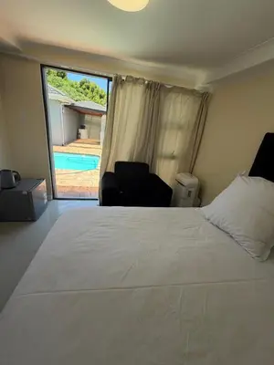 a bedroom with a large bed and a view of a pool at Joy House in Cape Town