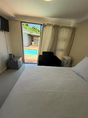 a bedroom with a bed and a chair and a pool at Joy House in Cape Town