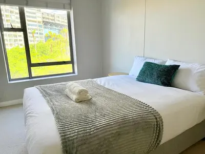 a bedroom with a bed with two towels on it at Luxe Manhattan Quarters in Cape Town