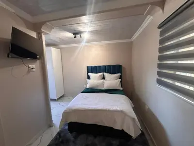 a small bedroom with a bed with a blue headboard at New Dawn Guest House in Goodwood