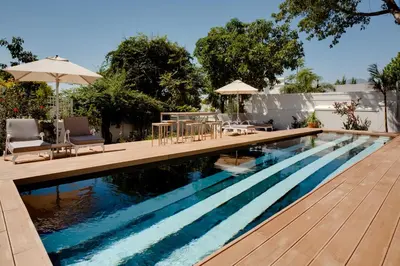 a swimming pool with a deck and chairs and an umbrella at Majeka House Boutique Hotel by The Living Journey Collection in Stellenbosch