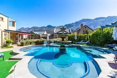 a large swimming pool with a fountain in a yard at L'Ermitage Villa Francois in Franschhoek