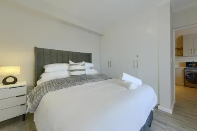 a bedroom with a large white bed with white pillows at Nua Chic Stylish 1Bedroom - 2mins to Beach in Cape Town