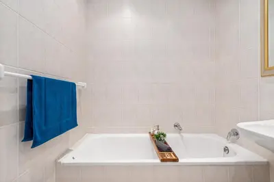 a bathroom with a bath tub with a blue towel at Gordons Village View in Cape Town