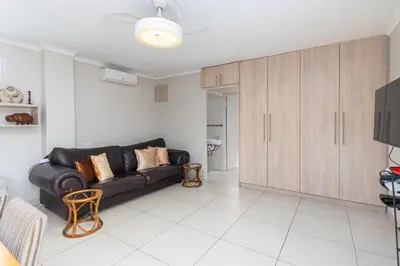 a living room with a black leather couch and cabinets at Entire large 1 bedroom very private with parking in Cape Town