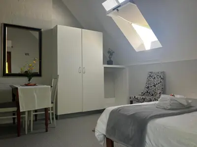 a bedroom with a bed and a table and a mirror at Starry Starry Night Loft, with Aircon in Die Boord in Stellenbosch
