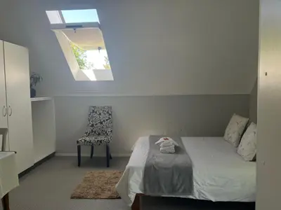 a bedroom with a bed and a chair and a skylight at Starry Starry Night Loft, with Aircon in Die Boord in Stellenbosch