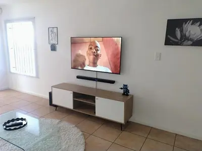 a living room with a flat screen tv on a wall at Polaris House in Cape Town