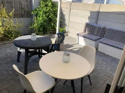 two tables and chairs and a bench on a patio at Polaris House in Cape Town