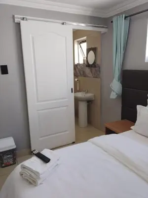 a bedroom with a white bed with a door and a sink at Edion Royal Guesthouse in Cape Town