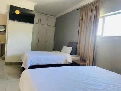 a hotel room with two beds and a window at Edion Royal Guesthouse in Cape Town