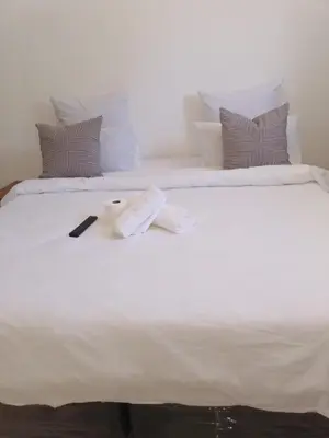 a white bed with a towel and a book on it at Edion Royal Guesthouse in Cape Town