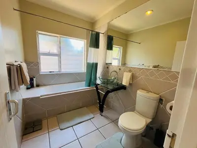 a bathroom with a tub and a toilet and a sink at 4 Bedroom Bliss in Cape Town