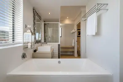 a white bathroom with a tub and a sink at Harbour House Hotel in Hermanus
