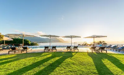 a group of tables and chairs with umbrellas on the grass at Harbour House Hotel in Hermanus