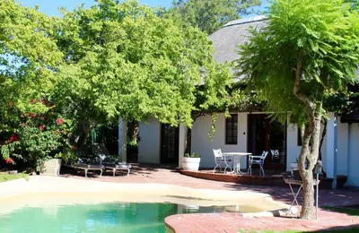 a house with a table and chairs next to a swimming pool at Wedgeview Country House & Spa in Stellenbosch