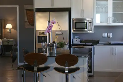 a kitchen with white cabinets and a table with chairs at Wedgeview Country House & Spa in Stellenbosch
